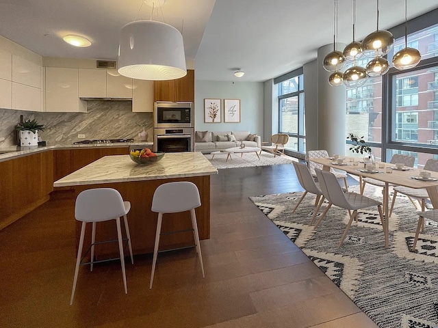 kitchen featuring a breakfast bar, decorative backsplash, appliances with stainless steel finishes, a kitchen island, and white cabinetry