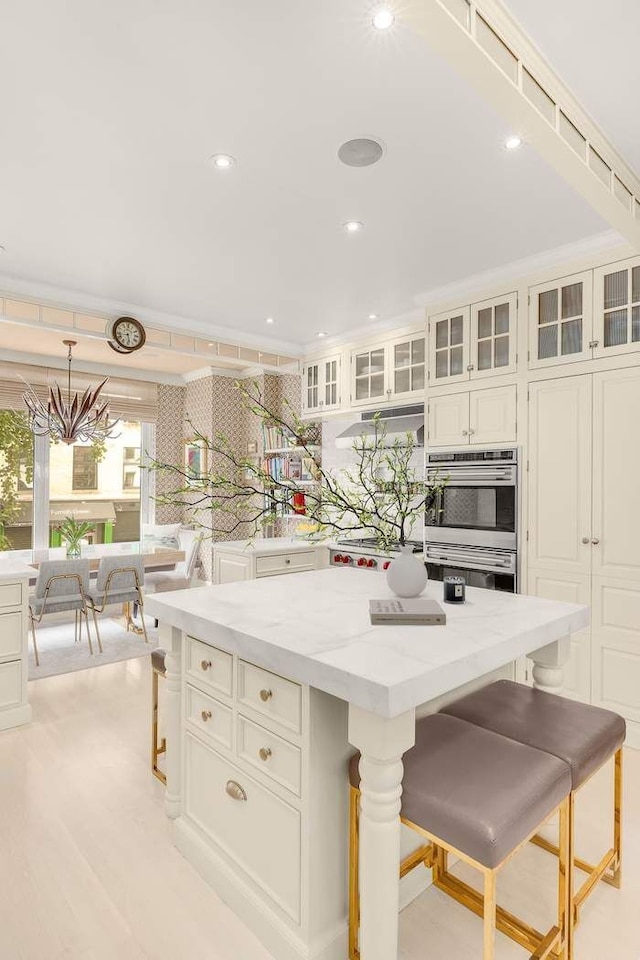 kitchen featuring light stone countertops, a center island, a kitchen bar, and stainless steel double oven