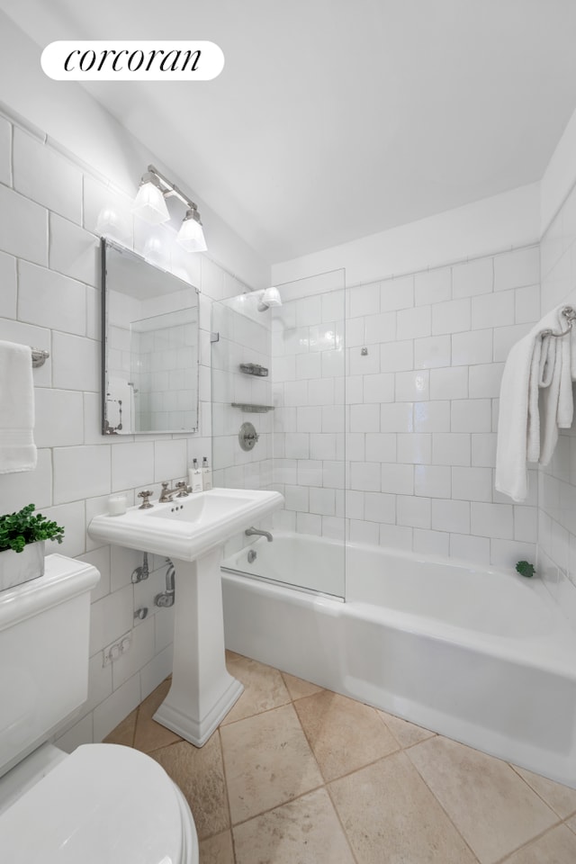 bathroom with tile walls, tiled shower / bath combo, toilet, and tile patterned flooring