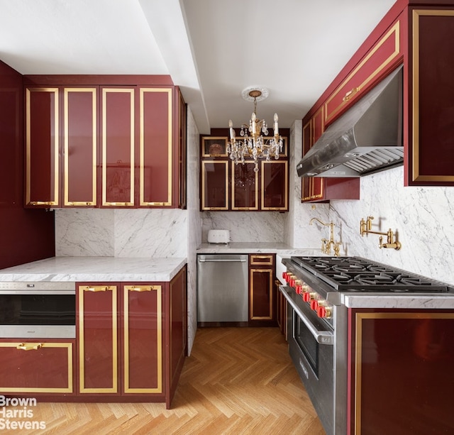 kitchen with wall chimney exhaust hood, pendant lighting, appliances with stainless steel finishes, light parquet flooring, and tasteful backsplash