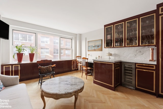 bar featuring light parquet floors, dark brown cabinets, backsplash, and beverage cooler