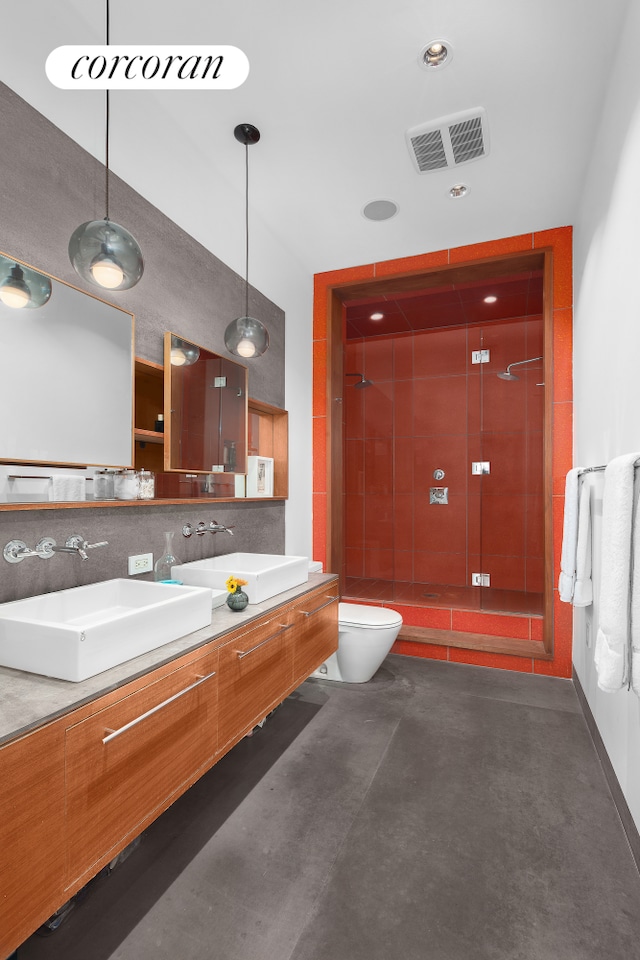 bathroom with concrete floors, vanity, a shower with shower door, and toilet