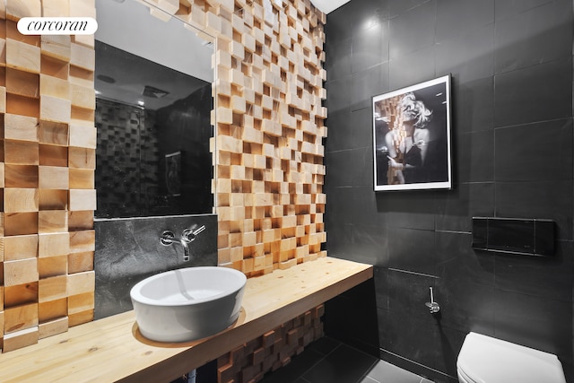 bathroom with tile patterned floors, tile walls, and toilet