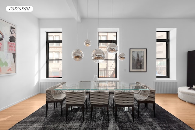 dining room featuring hardwood / wood-style floors, beamed ceiling, and a wealth of natural light