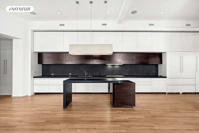 kitchen featuring tasteful backsplash, decorative light fixtures, light hardwood / wood-style flooring, beamed ceiling, and white cabinetry