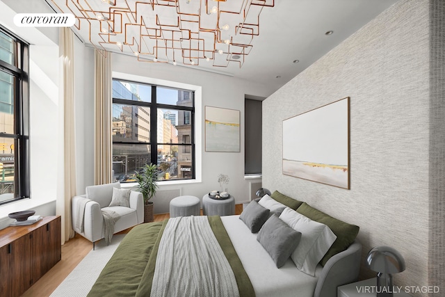 bedroom featuring multiple windows, an inviting chandelier, and light wood-type flooring