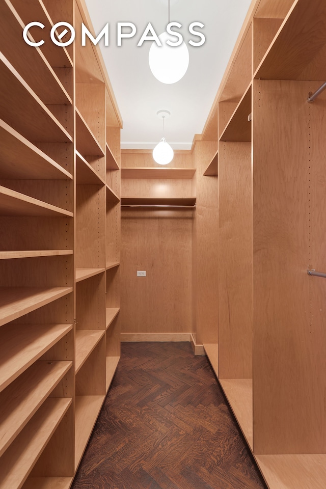 walk in closet with dark parquet floors