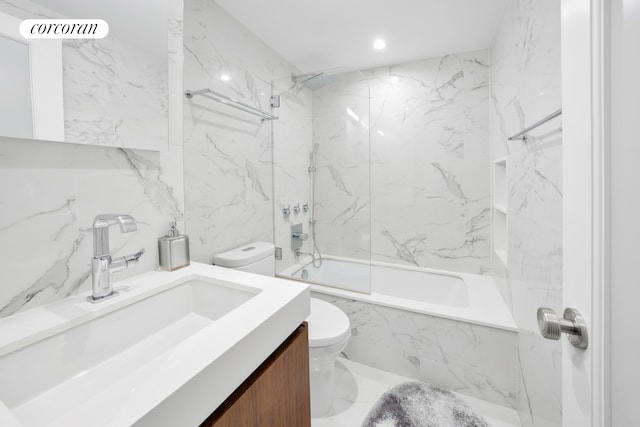 full bathroom featuring vanity, tiled shower / bath combo, toilet, and tile walls