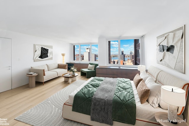 bedroom featuring a wall of windows and light hardwood / wood-style flooring