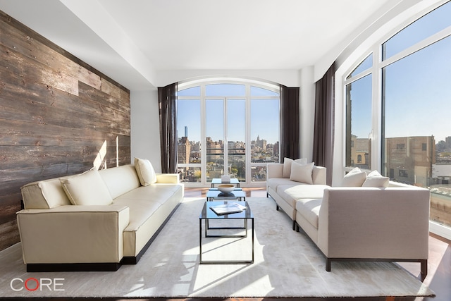 living room with hardwood / wood-style flooring, wood walls, and plenty of natural light