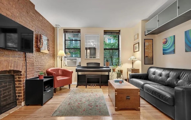 living room featuring decorative columns, brick wall, cooling unit, and light wood-type flooring