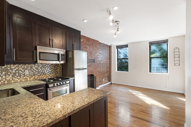 kitchen featuring appliances with stainless steel finishes, light stone counters, dark brown cabinets, and light hardwood / wood-style floors