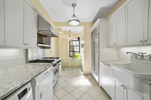 kitchen with tasteful backsplash, high quality appliances, white cabinets, washer / clothes dryer, and hanging light fixtures