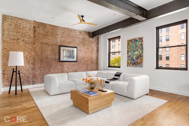 living room with ceiling fan, brick wall, wood-type flooring, and beamed ceiling