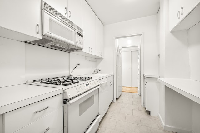 kitchen featuring sink, white cabinets, white appliances, and light tile patterned flooring