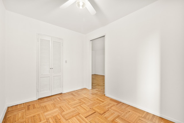 unfurnished bedroom featuring a closet, light parquet flooring, and ceiling fan