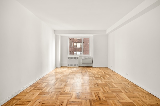 empty room featuring light parquet flooring, radiator heating unit, and a wall mounted air conditioner