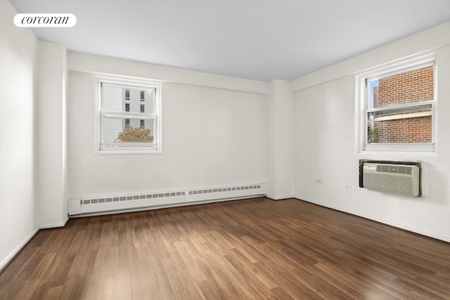 empty room featuring a wall mounted air conditioner, wood-type flooring, and a baseboard radiator