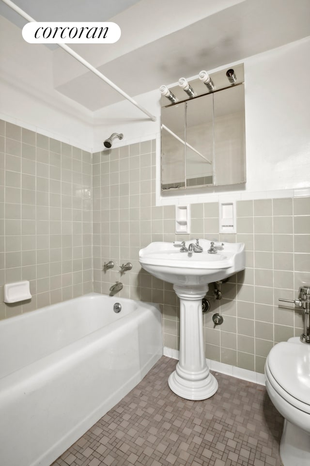 bathroom featuring toilet, tiled shower / bath, and tile walls