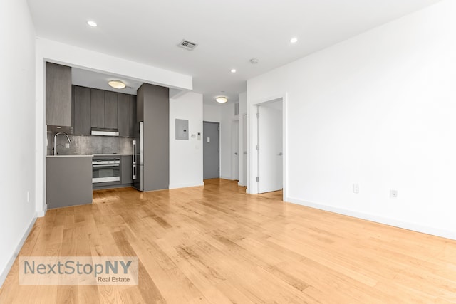 unfurnished living room featuring sink and light hardwood / wood-style flooring