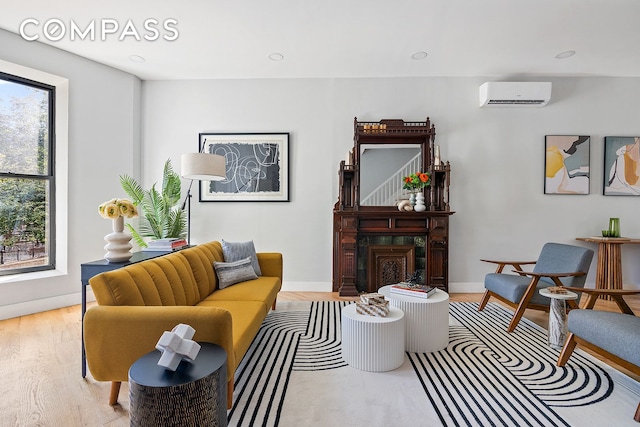 living room with light hardwood / wood-style floors and a wall unit AC