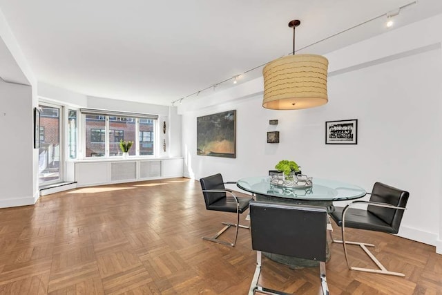 dining space with track lighting and parquet floors