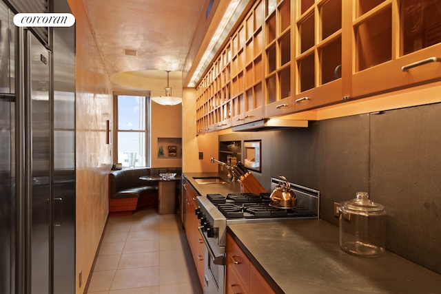 kitchen featuring sink, decorative light fixtures, light tile patterned floors, and premium appliances