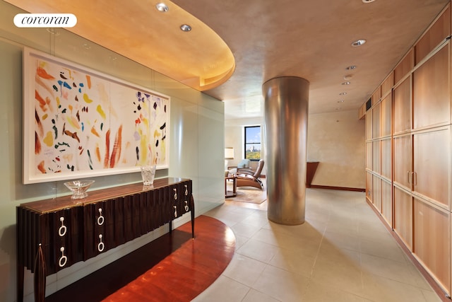 corridor featuring light tile patterned floors and decorative columns