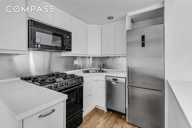 kitchen with light hardwood / wood-style floors, black appliances, sink, and white cabinets