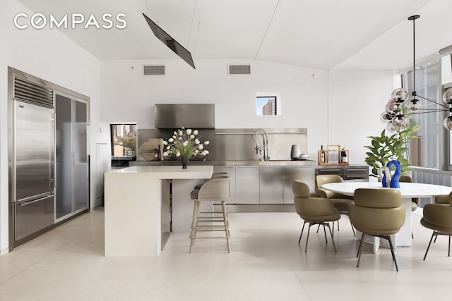 kitchen featuring a kitchen breakfast bar, lofted ceiling, decorative light fixtures, and built in fridge