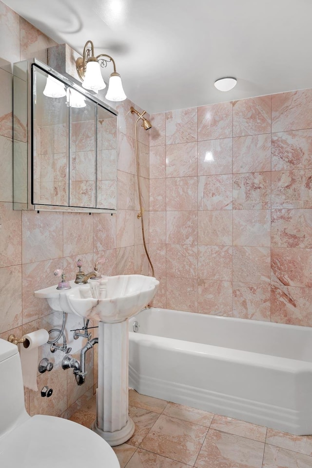 bathroom featuring toilet, tiled shower / bath combo, tile walls, and tile patterned flooring