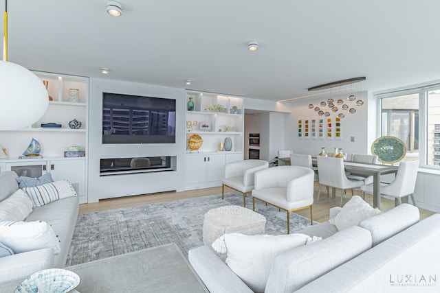 living room featuring light wood-type flooring and built in shelves