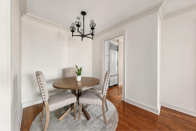 dining space with dark wood-type flooring, an inviting chandelier, and ornamental molding