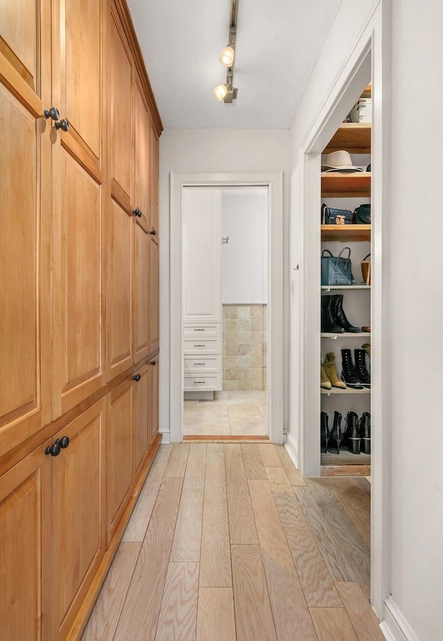 corridor featuring track lighting and light hardwood / wood-style floors