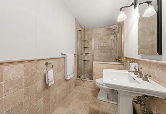 bathroom featuring tile walls, toilet, and a shower with door