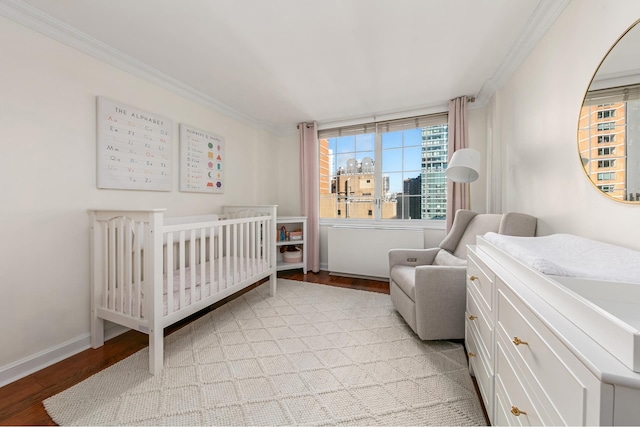 bedroom featuring ornamental molding, a nursery area, and light hardwood / wood-style floors