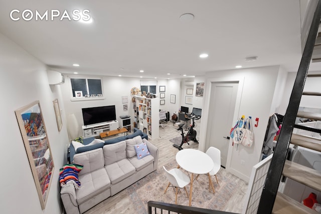 living room with light hardwood / wood-style flooring and a wall unit AC