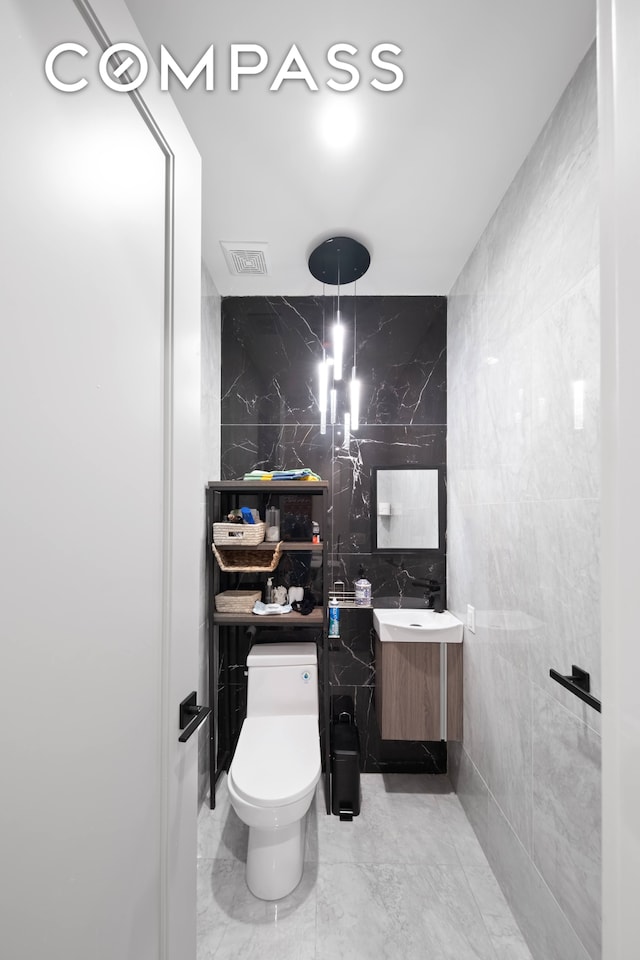 bathroom featuring tile walls, vanity, and toilet