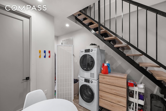 laundry area with hardwood / wood-style floors and stacked washer / dryer