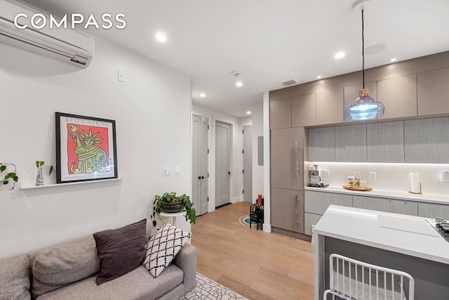 kitchen featuring light wood-type flooring, an AC wall unit, pendant lighting, and gray cabinets