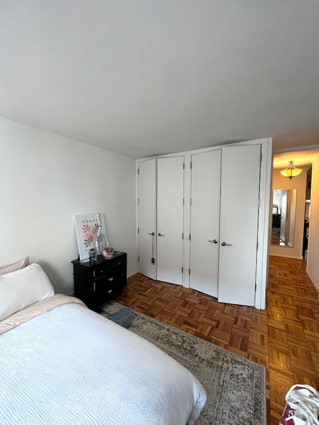 bedroom featuring multiple closets and dark parquet floors