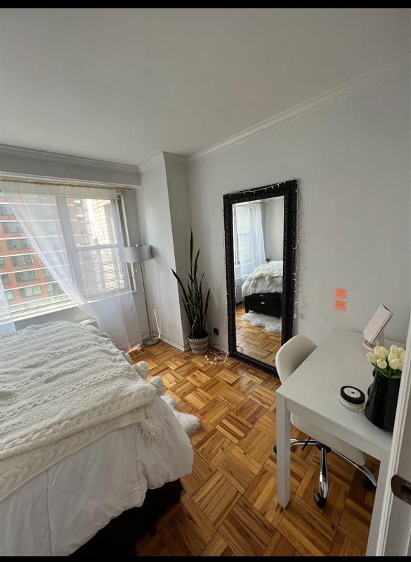 bedroom with ornamental molding and light parquet floors