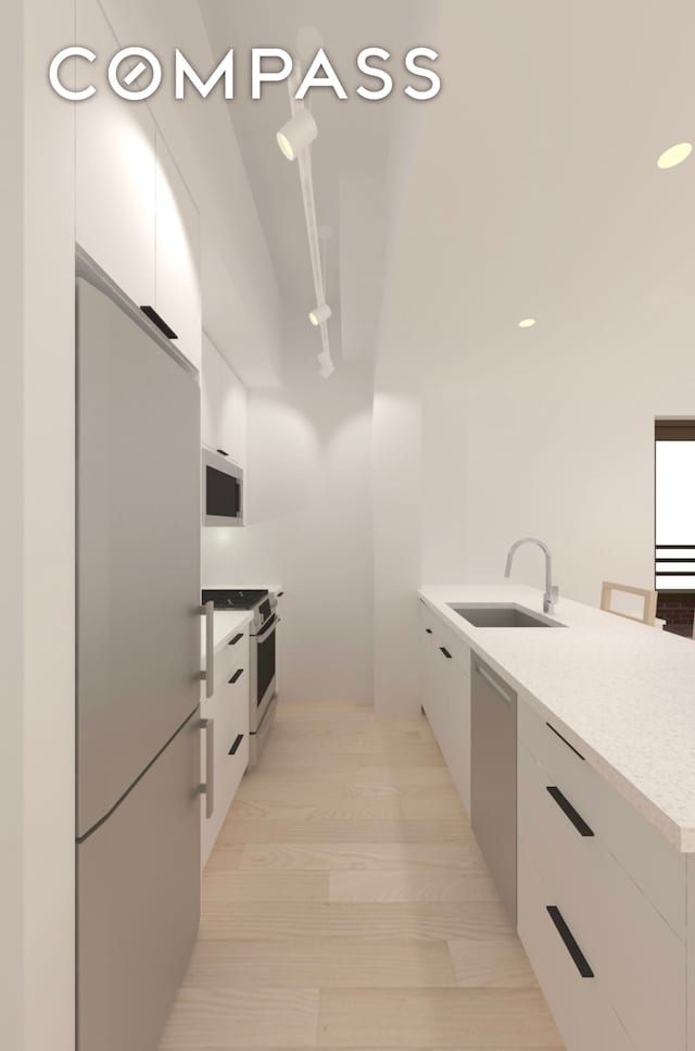 kitchen with light wood-type flooring, white cabinetry, sink, and appliances with stainless steel finishes