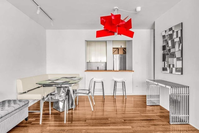 dining area with wood-type flooring and rail lighting