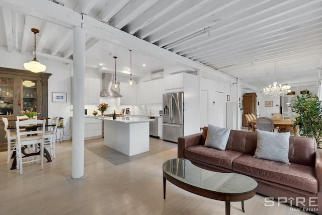 living room with a notable chandelier, light hardwood / wood-style floors, sink, and beam ceiling