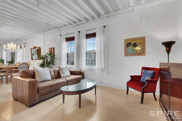 living room featuring a chandelier, light hardwood / wood-style flooring, beamed ceiling, and brick wall