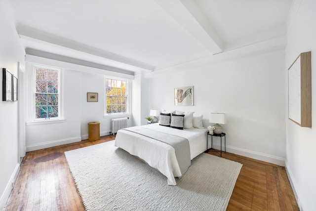 bedroom featuring radiator, beamed ceiling, and hardwood / wood-style floors