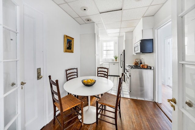 dining space featuring dark hardwood / wood-style flooring and a paneled ceiling