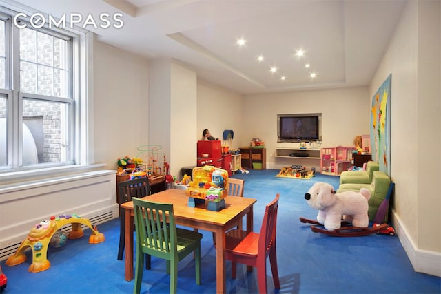 recreation room with a tray ceiling and carpet flooring