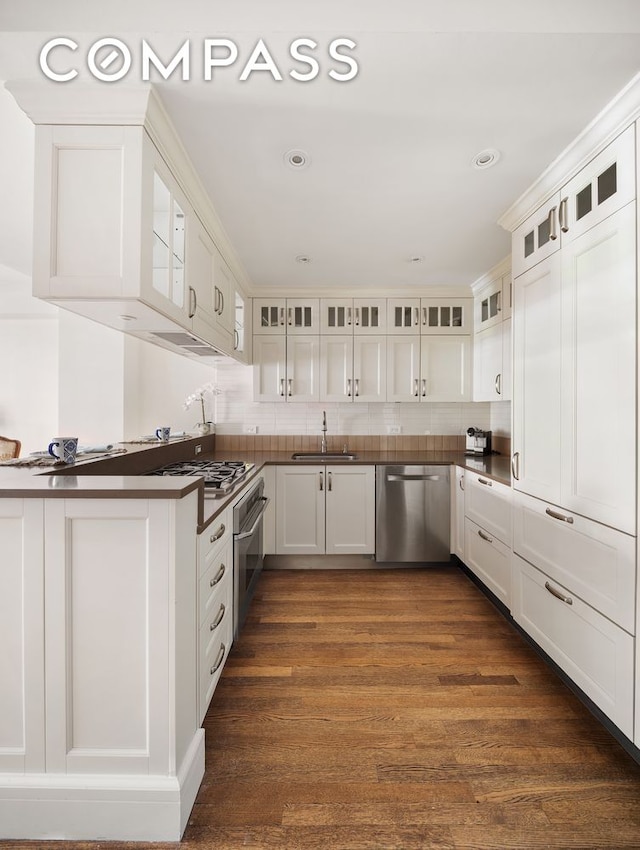 kitchen with white cabinetry, appliances with stainless steel finishes, backsplash, dark hardwood / wood-style flooring, and sink